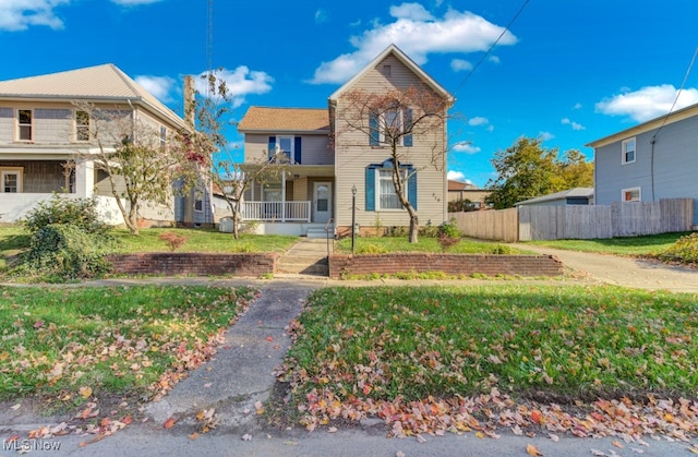 view of front of property with a front yard, covered porch, and fence