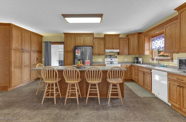 kitchen with a kitchen island, stainless steel fridge, white dishwasher, and a sink