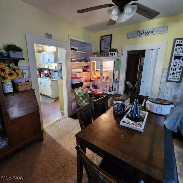 carpeted dining room with ceiling fan