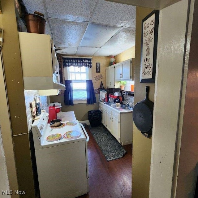 kitchen featuring dark wood-type flooring, white cabinets, white stove, and a paneled ceiling