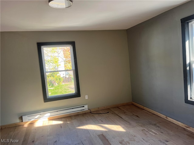 spare room with a baseboard heating unit and light wood-type flooring