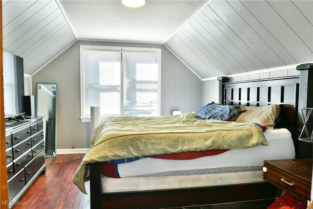 bedroom with lofted ceiling, dark hardwood / wood-style floors, and wood walls