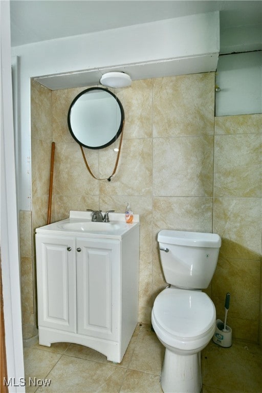 bathroom with vanity, toilet, tile patterned floors, and tile walls