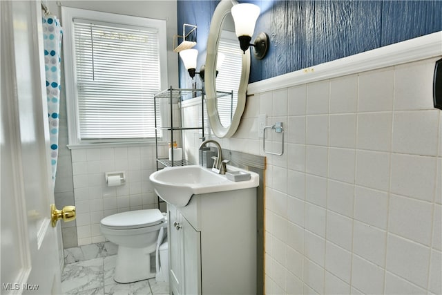 bathroom featuring vanity, toilet, and tile walls