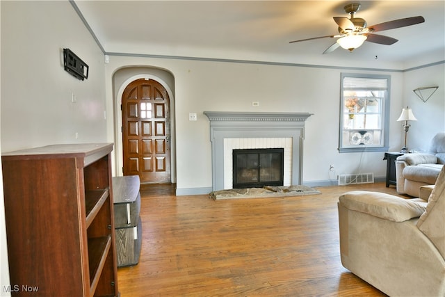 living room with ornamental molding, wood-type flooring, and ceiling fan