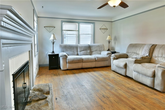 living room with ceiling fan, wood-type flooring, and a fireplace