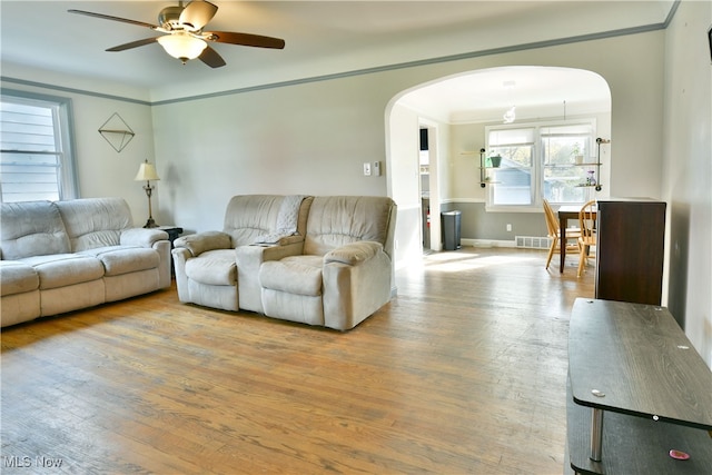 living room with ceiling fan, ornamental molding, and light hardwood / wood-style flooring