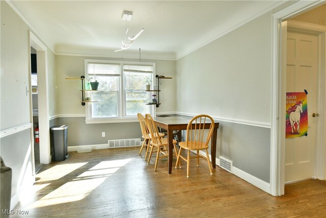 dining room featuring light hardwood / wood-style floors and crown molding