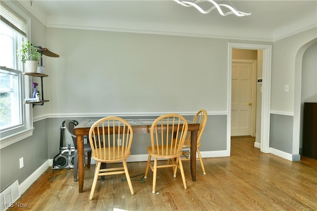 dining area with ornamental molding, light hardwood / wood-style floors, and a healthy amount of sunlight