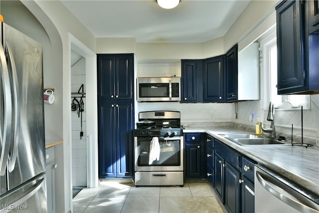 kitchen with light tile patterned flooring, appliances with stainless steel finishes, sink, and decorative backsplash