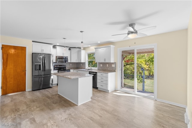 kitchen with hanging light fixtures, stainless steel appliances, backsplash, a center island, and white cabinets