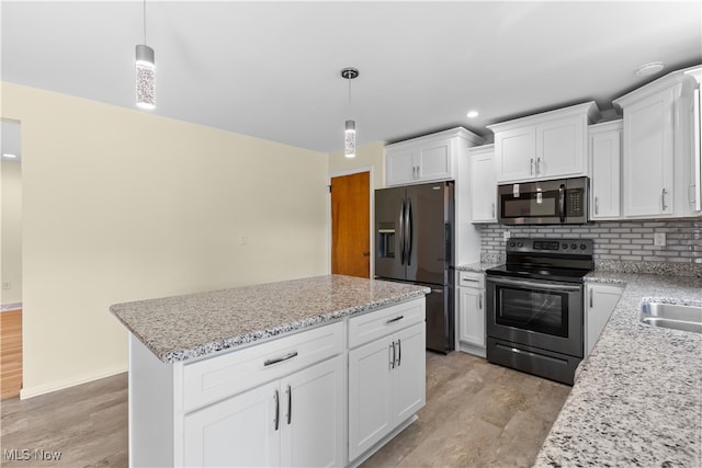 kitchen featuring appliances with stainless steel finishes, light hardwood / wood-style flooring, pendant lighting, and white cabinetry