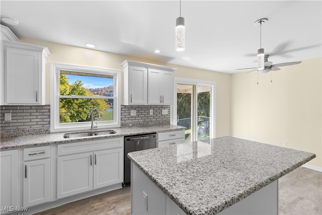 kitchen featuring decorative backsplash, white cabinetry, stainless steel dishwasher, sink, and a center island