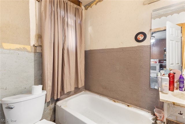 bathroom with tile walls, toilet, and a bath