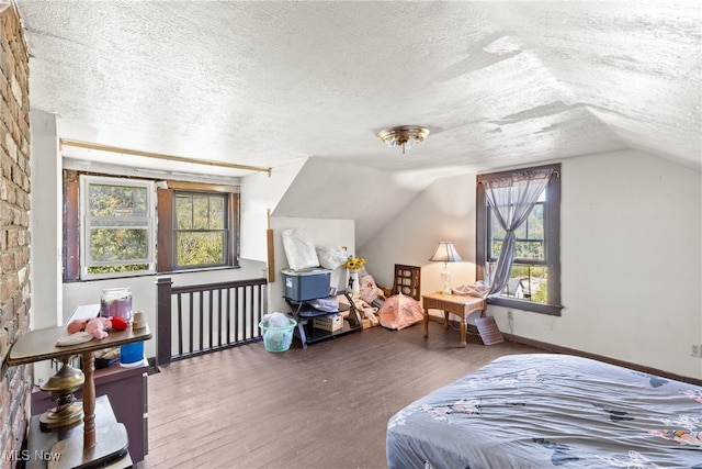 bedroom with lofted ceiling, a textured ceiling, and hardwood / wood-style flooring