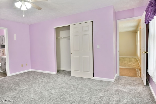 unfurnished bedroom featuring light carpet, a closet, and ceiling fan