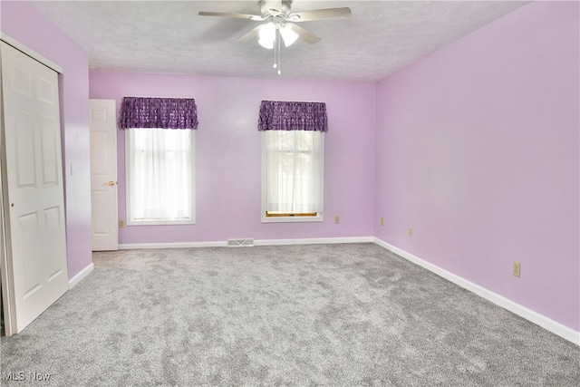 carpeted spare room with a textured ceiling and ceiling fan