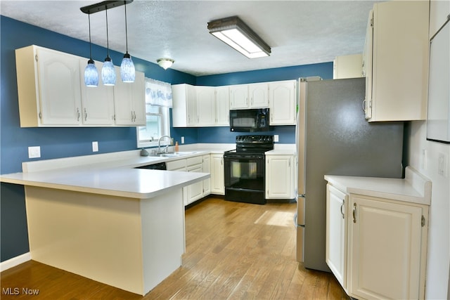 kitchen with kitchen peninsula, white cabinets, black appliances, sink, and decorative light fixtures