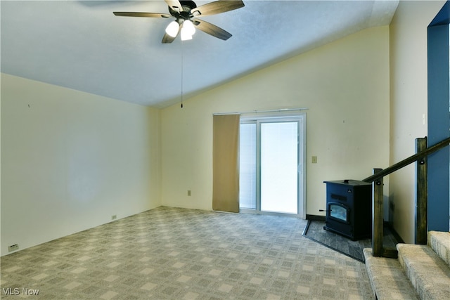 unfurnished living room with light carpet, a wood stove, ceiling fan, and vaulted ceiling