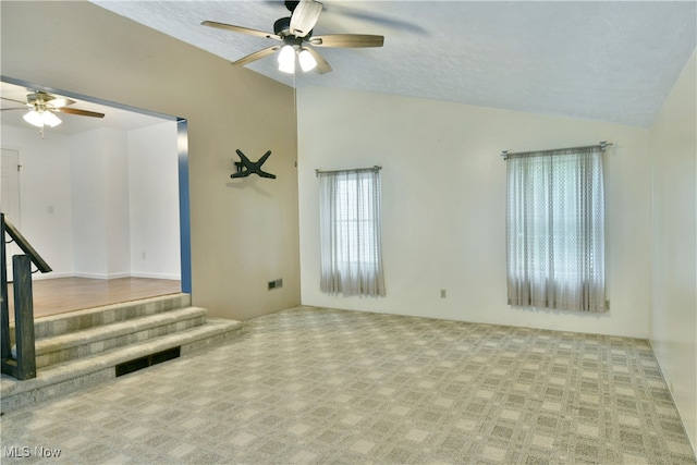 spare room featuring vaulted ceiling, a textured ceiling, and ceiling fan