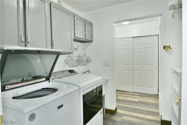 laundry room featuring dark wood-type flooring, cabinets, and washing machine and clothes dryer