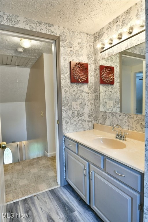 bathroom featuring vanity, lofted ceiling, hardwood / wood-style floors, and a textured ceiling