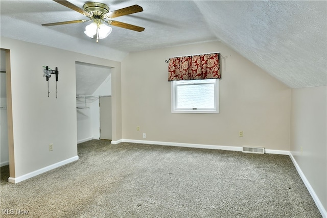 bonus room featuring carpet, a textured ceiling, lofted ceiling, and ceiling fan