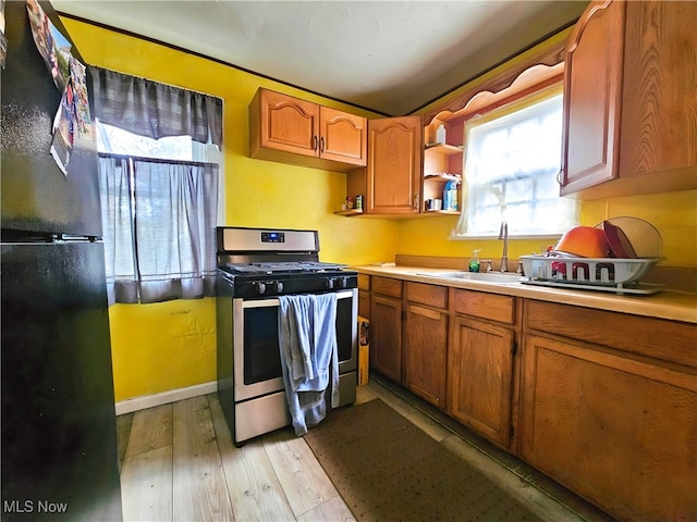 kitchen with sink, black fridge, light wood-type flooring, and double oven range