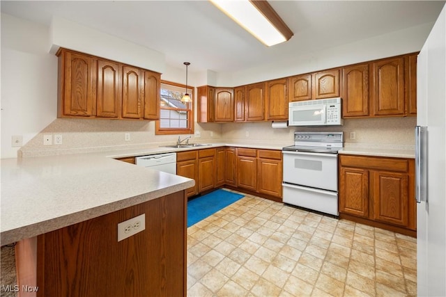 kitchen with decorative light fixtures, kitchen peninsula, sink, and white appliances