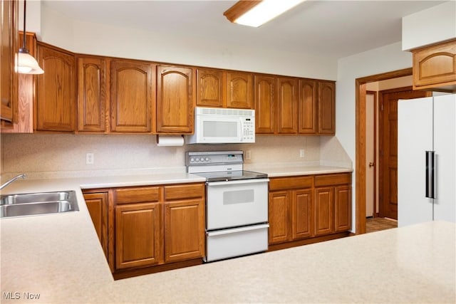 kitchen with decorative backsplash, sink, hanging light fixtures, and white appliances