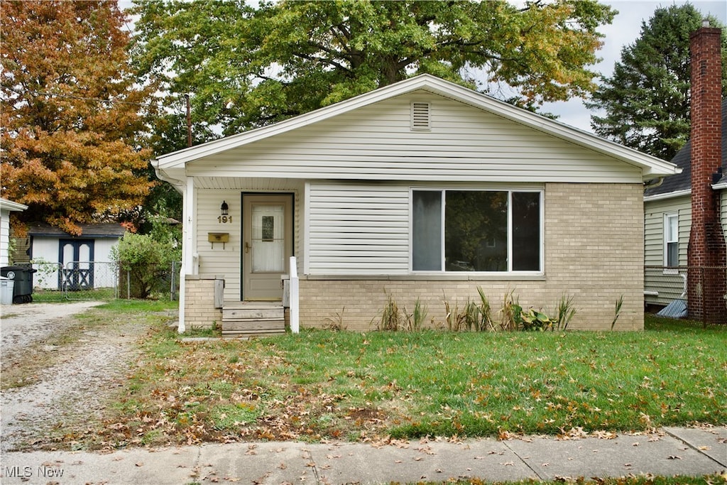 bungalow with a front yard and a storage unit