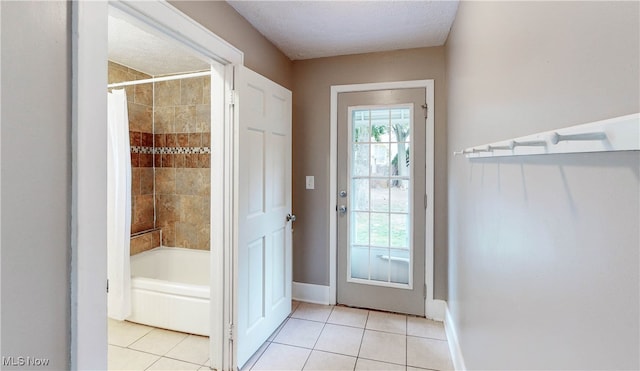 doorway with a textured ceiling and light tile patterned flooring