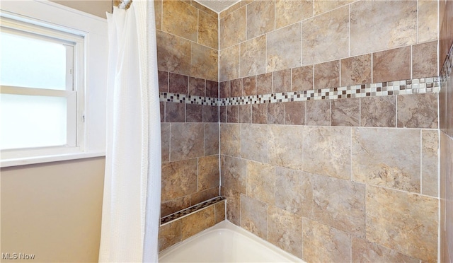 bathroom with a healthy amount of sunlight and shower / bathtub combination with curtain