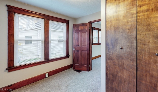 hallway with a textured ceiling and light colored carpet