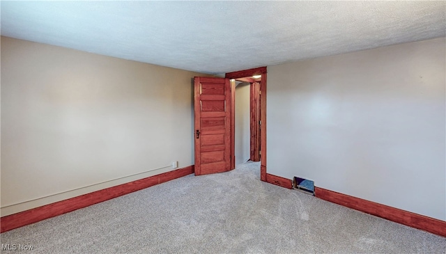 empty room featuring light carpet and a textured ceiling