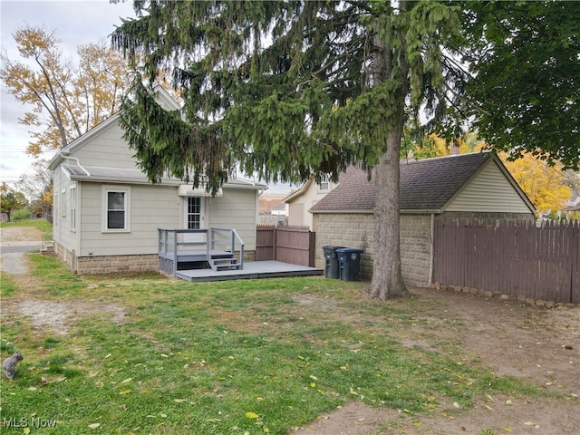 back of property with a wooden deck and a lawn