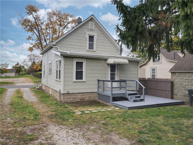 rear view of house with a wooden deck and a lawn