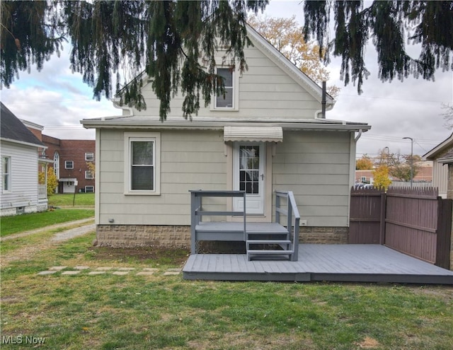 back of house with a deck and a lawn