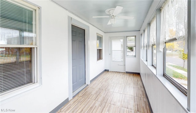 unfurnished sunroom featuring ceiling fan and a wealth of natural light