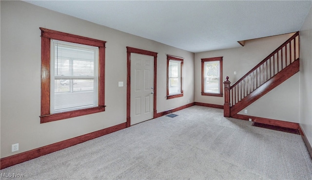 entryway featuring light carpet and a textured ceiling