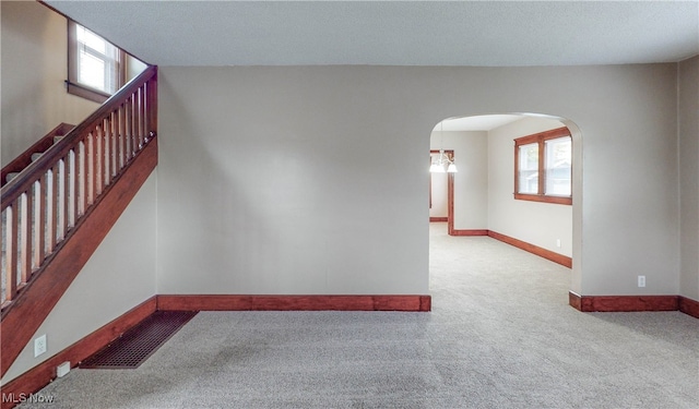 empty room with a textured ceiling and light colored carpet