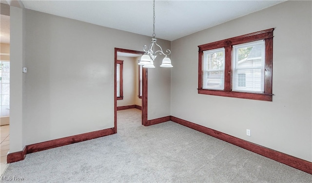 empty room with a notable chandelier and light colored carpet