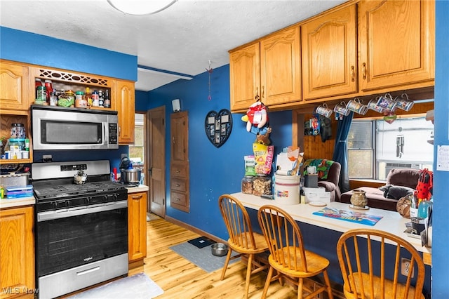 kitchen featuring cooling unit, a textured ceiling, stainless steel appliances, and light wood-type flooring