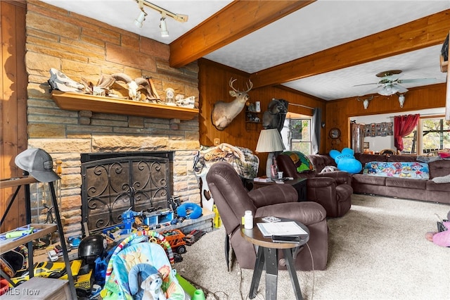 living room with wood walls, beam ceiling, carpet flooring, a fireplace, and ceiling fan