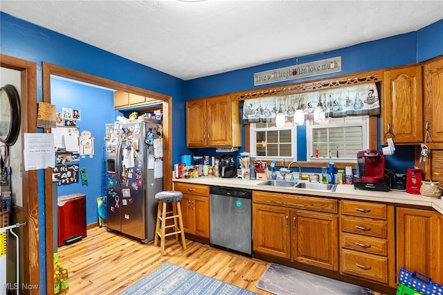 kitchen with stainless steel appliances, sink, and light wood-type flooring