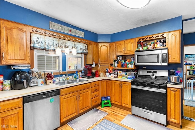 kitchen featuring stainless steel appliances, sink, and light wood-type flooring