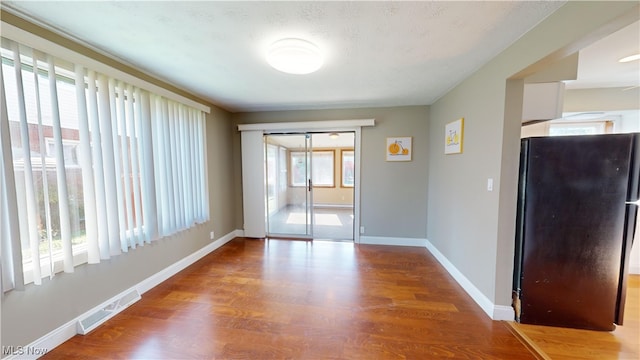 spare room featuring a textured ceiling, hardwood / wood-style flooring, and plenty of natural light