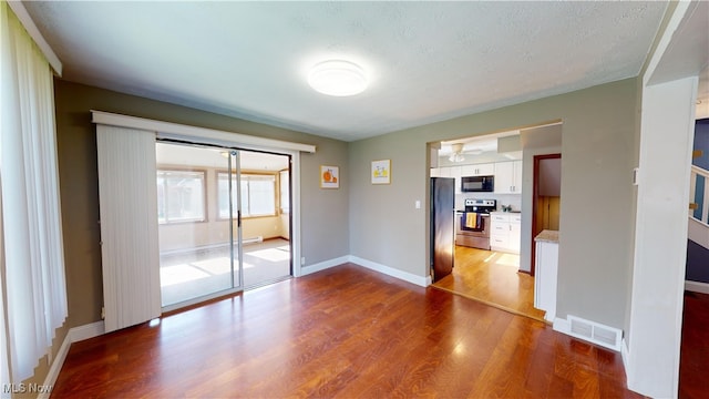 empty room with light hardwood / wood-style floors, a textured ceiling, and ceiling fan