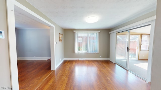 empty room with a textured ceiling and wood-type flooring