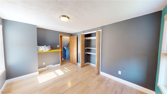 unfurnished bedroom with a closet, a textured ceiling, and light wood-type flooring